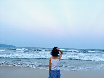 Woman standing on beach against sea against sky