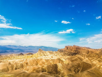 Scenic view of arid landscape against blue sky