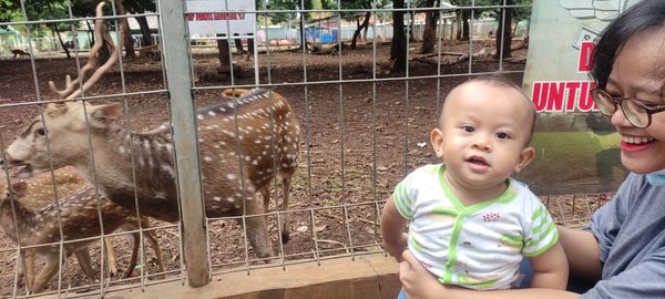 Portrait of cute boy and fence outdoors