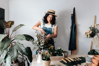 Woman standing by potted plants on table