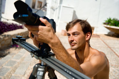 Shirtless man photographing through camera