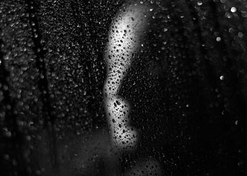 Close-up of wet window against black background