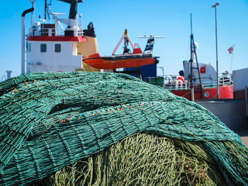 Fishing nets by boats at harbor against sky