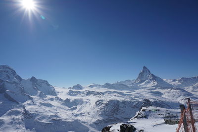 Scenic view of snow covered mountains against blue sky