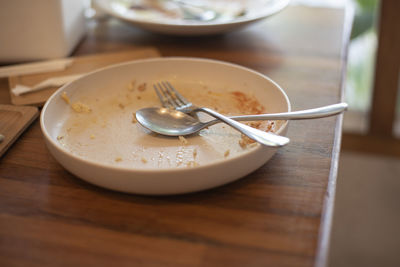 Spoon and fork are placed on an empty plate after eating. represents eating that is not thrown away 