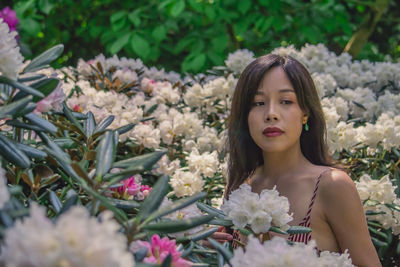 Portrait of beautiful woman against white flowering plants