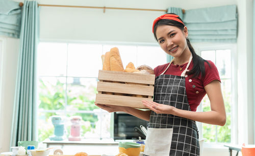 Portrait of smiling chef holding croissants in box