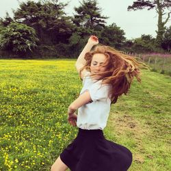 Young woman dancing by buttercup flowers growing on field