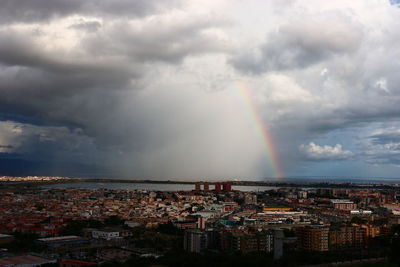 Aerial view of rainbow over buildings in city against sky