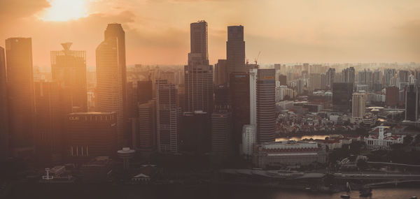 Modern buildings in city against sky during sunset