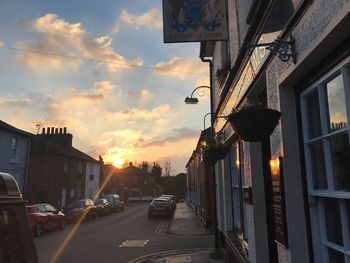 Cars on street in city against sky at sunset