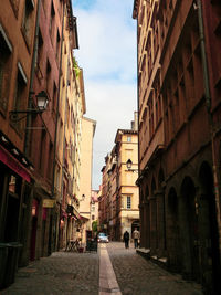 Narrow street amidst buildings in city against sky