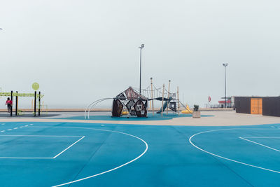 Outdoor play equipment in court against sky at playground