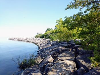 Rocks by sea against clear sky