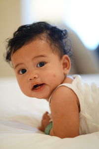 Portrait of cute girl sitting on bed at home