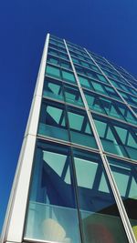 Low angle view of glass building against clear blue sky