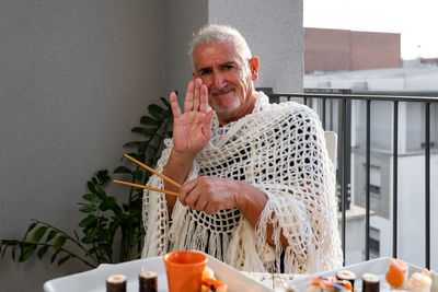 Attractive middle-aged man have fun while eating sitting at a table laid chinese  food on a terrace