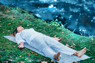 Corpse position, savasana, meditation. young woman practicing yoga and meditating by the water.