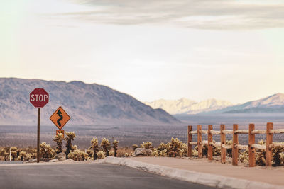 Road sign by mountains against sky