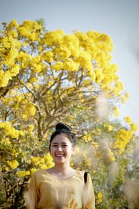 Portrait of smiling woman standing against trees