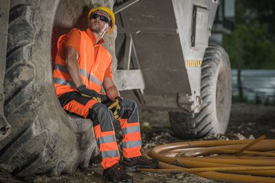 Worker sitting on tire of bulldozer at construction site