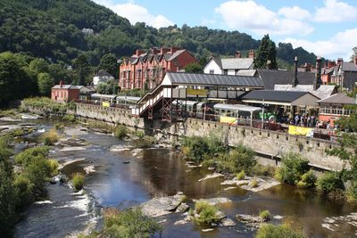 Buildings by river against sky