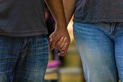 Midsection of couple holding hands