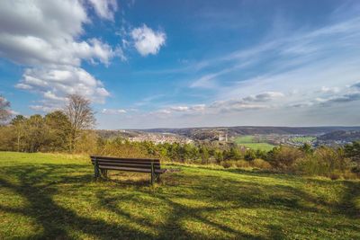 Park bench on field against sky