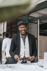 Smiling mature businessman holding tablet pc at office