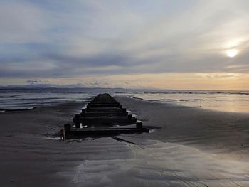 Lifeguard hut on beach against sky during sunset