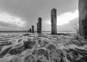 Wooden posts on beach against sky