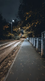 Empty road along trees at night
