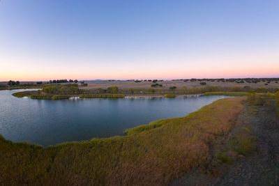 Scenic view of lake against clear sky during sunset