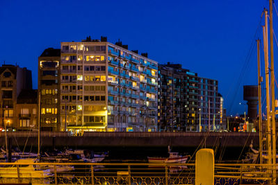 Illuminated buildings against clear blue sky at night