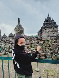 A boy stands on a fence near the plaosan temple in central java