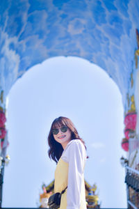 Portrait of young woman standing against sky