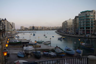 Boats moored at harbor against clear sky