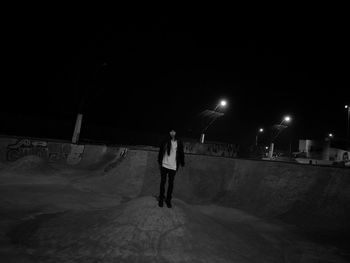 Full length of man walking on illuminated road against sky at night