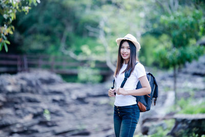Portrait of smiling young woman standing against blurred background