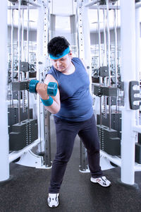 Full length of man holding dumbbell at gym