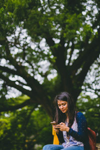 Young woman sitting on tree