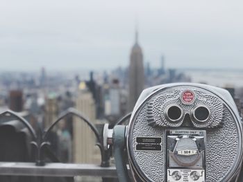 Close-up of coin-operated binoculars against buildings in city