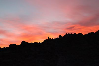 Silhouette buildings against dramatic sky during sunset