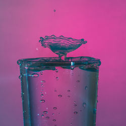 Close-up of water drops on glass against pink background
