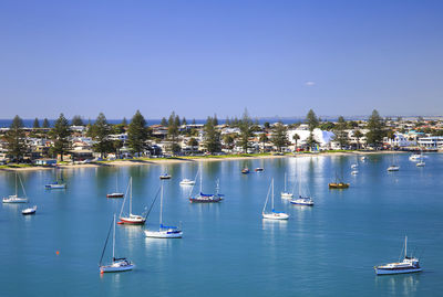 Sailboats moored on sea against clear blue sky