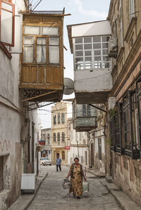 Rear view of people walking on street amidst buildings