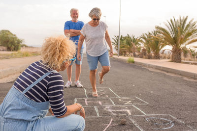 Family playing hopscotch on road outdoors