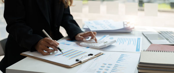 Midsection of businesswoman working on table