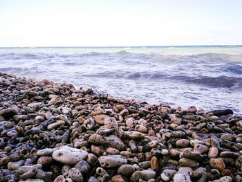 Pebbles on beach against clear sky