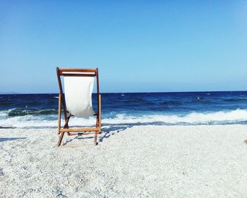 Deck chairs on beach against clear sky